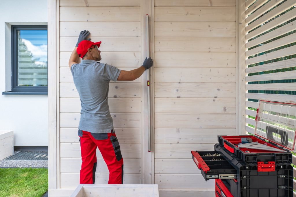 Contractor Using Level on Wooden Wall During Construction